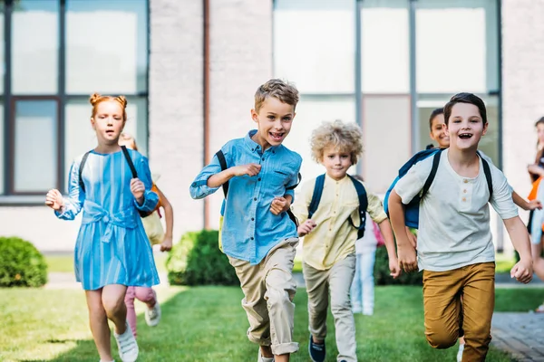 Группа восхищенных учёных, бегущих по школьному саду — стоковое фото