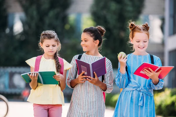 Glückliche Schulmädchen mit Notizbüchern, die nach der Schule Zeit miteinander verbringen — Stockfoto