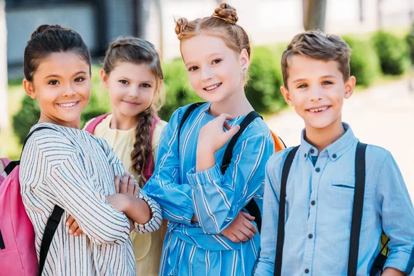 Grupo de escolares felices con mochilas mirando a la cámara - foto de stock