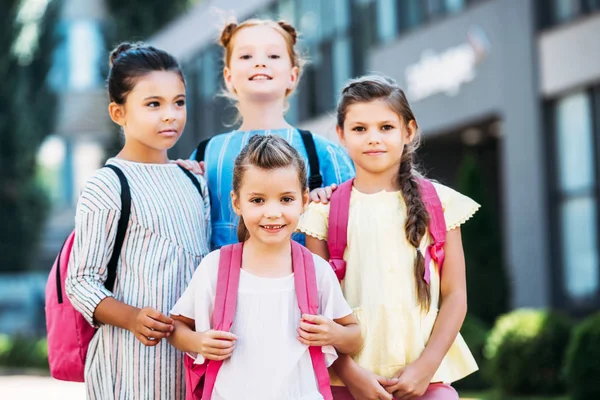 Group of adorable schoolgirls with backpacks looking at camera — Stock Photo