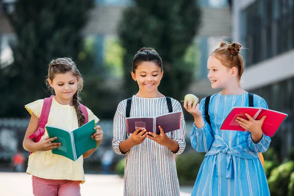 Schoolgirls with notebooks spending time together after school — Stock Photo