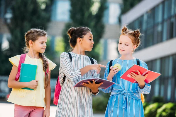 Schoolgirls with notebooks spending time together after school and discussing homework — Stock Photo