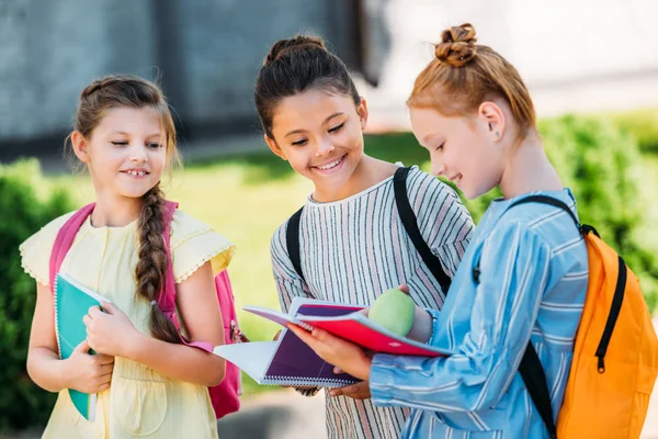 Group of happy schoolgirls with notebooks walking together after school — Stock Photo