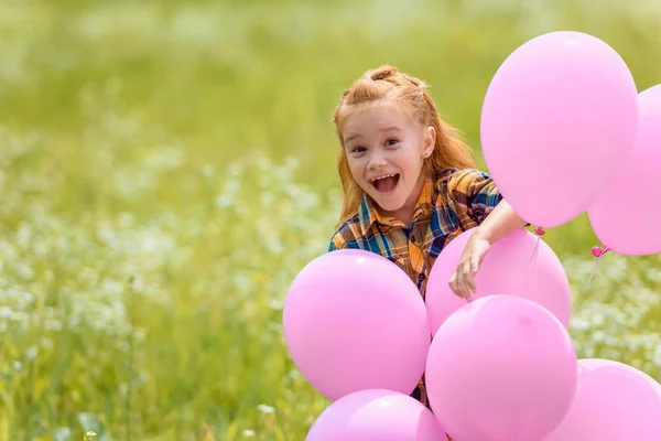 Ritratto di allegro adorabile bambino con palloncini rosa nel campo estivo — Foto stock