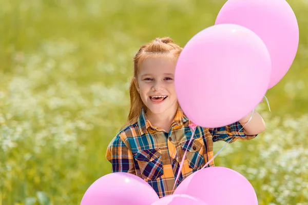 Retrato de niño feliz con globos rosados en el campo de verano - foto de stock