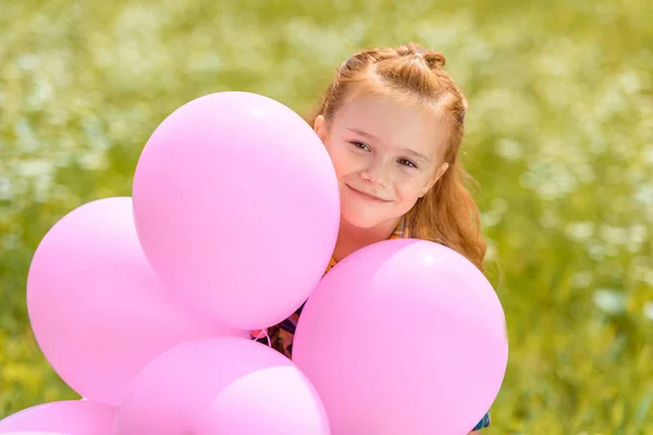 Портрет усміхненої чарівної дитини з рожевими кульками в літньому полі — стокове фото