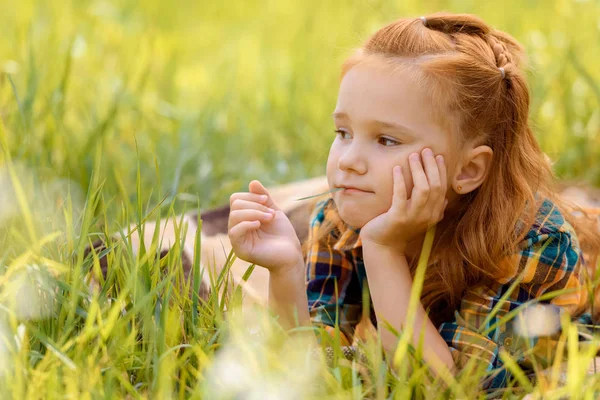 Retrato de un niño pensativo descansando sobre hierba verde en el prado - foto de stock