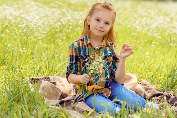 Lächelndes Kind mit Strauß wilder Blumen auf der Wiese — Stockfoto