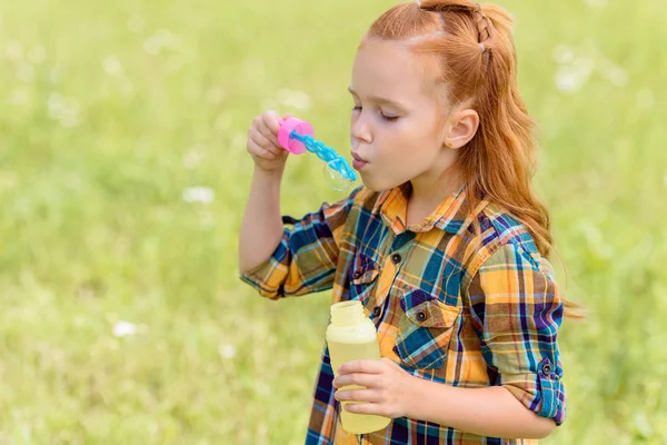 Ritratto di bambino che soffia bolle di sapone nel prato — Foto stock