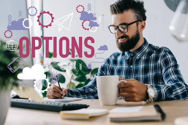 Successful businessman with cup of coffee and computer writing notes at workplace with options icons — Stock Photo