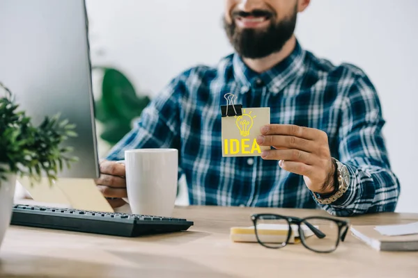 Recortado tiro de exitoso empresario sosteniendo nota adhesiva con idea de bombilla - foto de stock