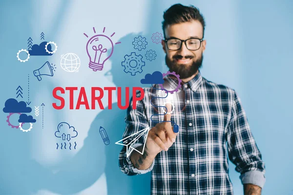 Lächelnder Geschäftsmann im karierten Hemd zeigt auf Start-up-Ikonen — Stockfoto