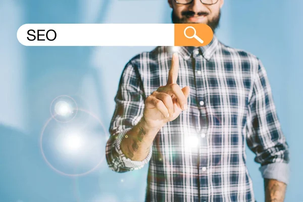 Cropped view of developer in checkered shirt pointing SEO search bar — Stock Photo