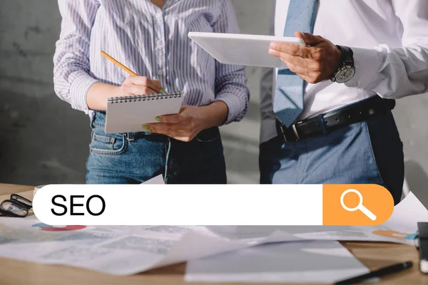 Cropped view of developers working with documents and digital tablet, with SEO search bar — Stock Photo