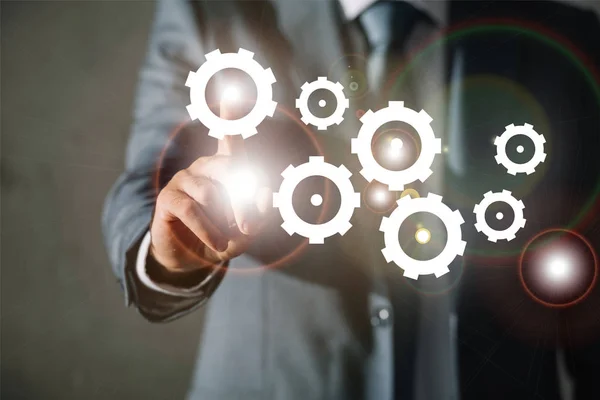 Cropped view of businessman in suit touching gears with finger — Stock Photo