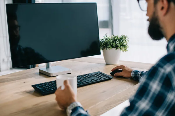 Abgeschnittene Aufnahme eines Mannes mit einer Tasse Kaffee am Computer mit leerem Bildschirm — Stockfoto