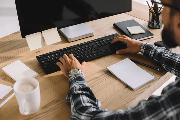 Plan recadré de l'homme barbu en chemise à carreaux en utilisant l'ordinateur sur le lieu de travail — Photo de stock