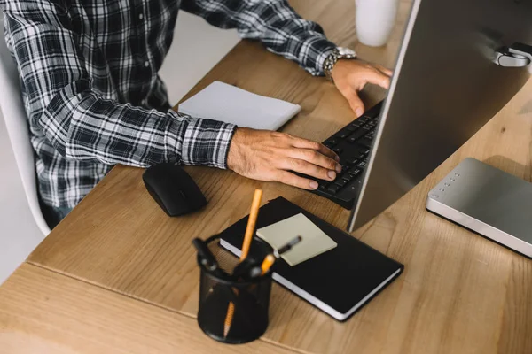 Cropped shot of man in plaid shirt using computer at workplace — Stock Photo