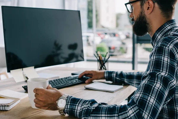 Giovane sviluppatore di successo seduto sul posto di lavoro con schermo del computer vuoto — Foto stock