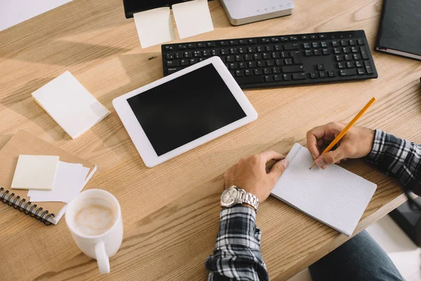 Tiro cortado de seo com tablet no local de trabalho fazendo anotações no bloco de notas — Fotografia de Stock