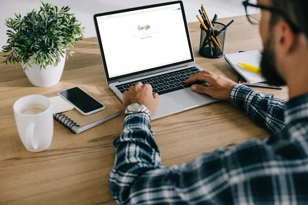 Cropped shot of man in plaid shirt using laptop with google website on screen — Stock Photo