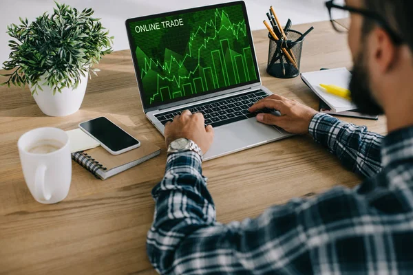 Recortado tiro del hombre en camisa a cuadros usando portátil con gráfico de comercio en línea en la pantalla - foto de stock