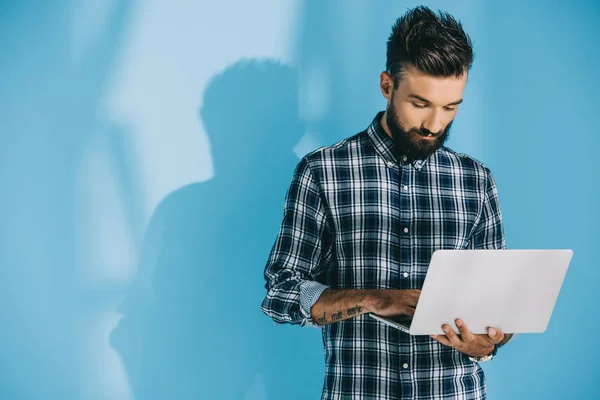 Красивый бородатый мужчина с ноутбуком, на голубом — стоковое фото