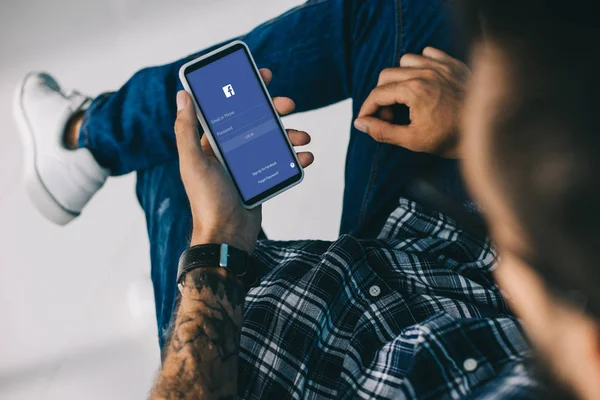 Partial view of man using smartphone with facebook app — Stock Photo