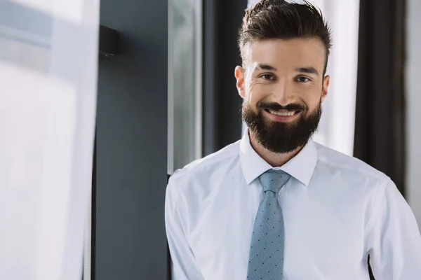 Retrato de belo empresário de pé perto da janela no escritório — Fotografia de Stock