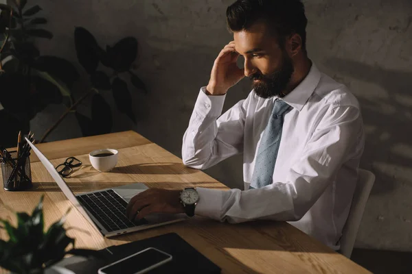 Hombre de negocios profesional pensativo usando el ordenador portátil en la oficina - foto de stock