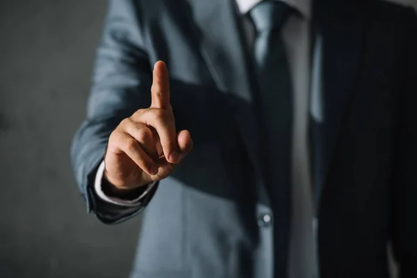 Vista cortada de homem de negócios em terno apontando para cima com o dedo — Fotografia de Stock