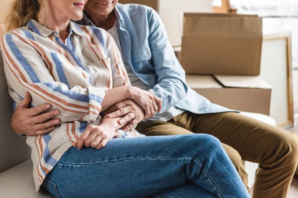 Schnappschuss eines glücklichen Senioren-Paares, das sich Händchen hält und zusammen auf der Couch im neuen Haus sitzt — Stockfoto