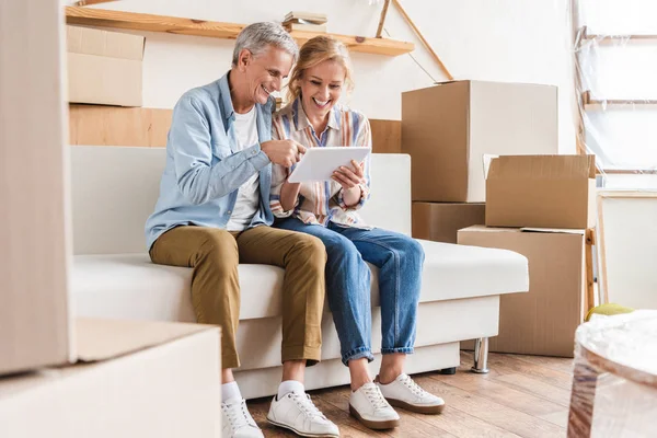 Smiling elderly couple using digital tablet while moving home — Stock Photo
