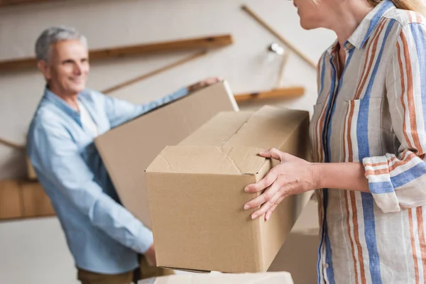 Cropped shot of senior couple holding cardboard boxes during relocation — Stock Photo