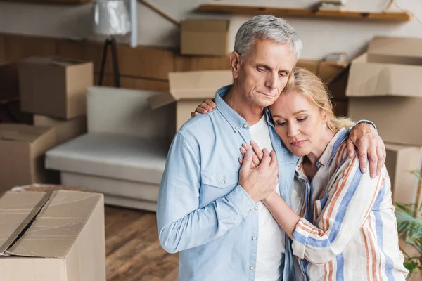 Vue en angle élevé du couple âgé bouleversé embrassant et tenant la main pendant la réinstallation — Photo de stock