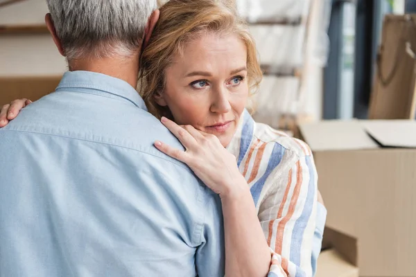 Cropped shot of grey hair man hugging pensive wife while moving home — Stock Photo