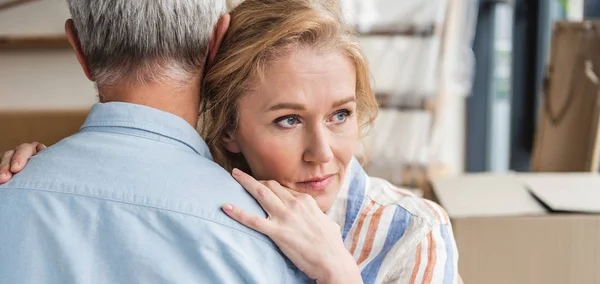 Cropped shot of senior man hugging pensive wife while moving home — Stock Photo