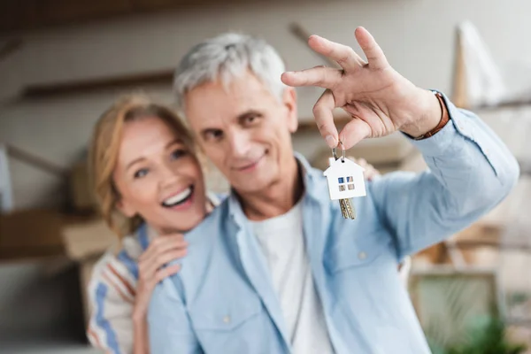 Happy senior couple holding keys from new nome during relocation — Stock Photo