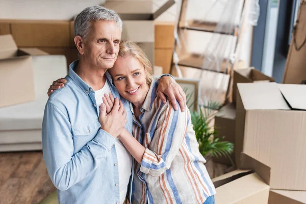 Vue grand angle de heureux couple de personnes âgées embrassant et tenant la main tout en déménageant à la maison — Photo de stock