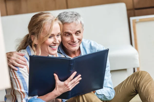 Hermosa feliz pareja de ancianos mirando álbum de fotos juntos - foto de stock