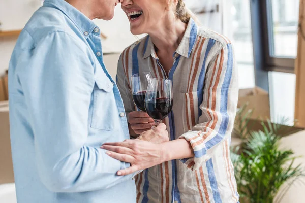Recortado disparo de feliz pareja de ancianos beber vino juntos en nueva casa - foto de stock