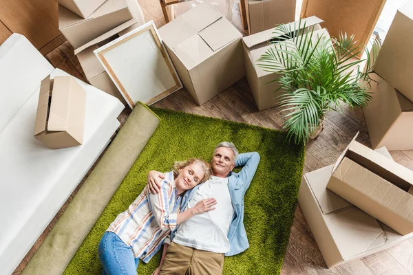 High angle view of happy senior couple lying on carpet while moving home — Stock Photo