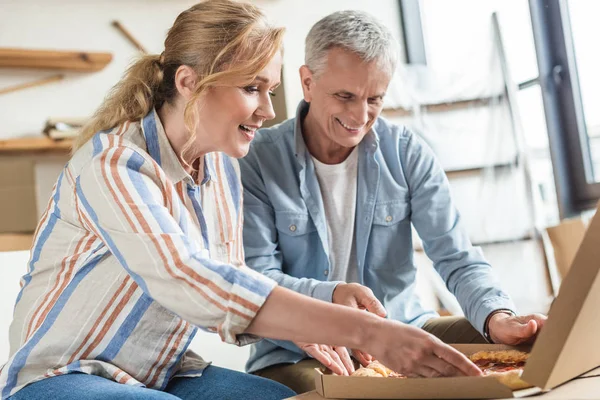 Happy senior couple eating pizza during relocation in new home — Stock Photo