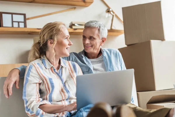 Happy senior couple using laptop and smiling each other during relocation — Stock Photo