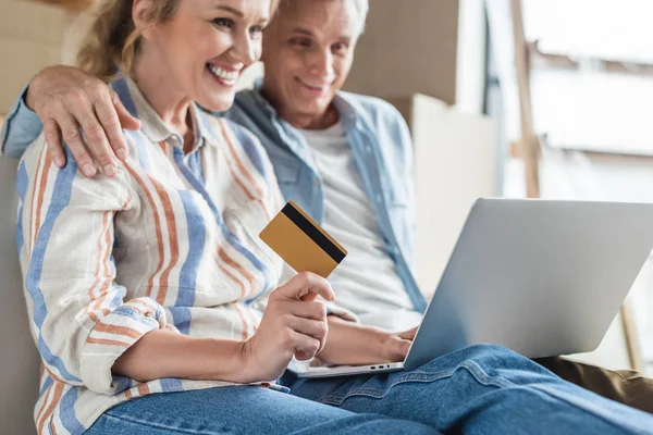 Plan recadré de couple âgé heureux à l'aide d'un ordinateur portable et tenant la carte de crédit — Photo de stock