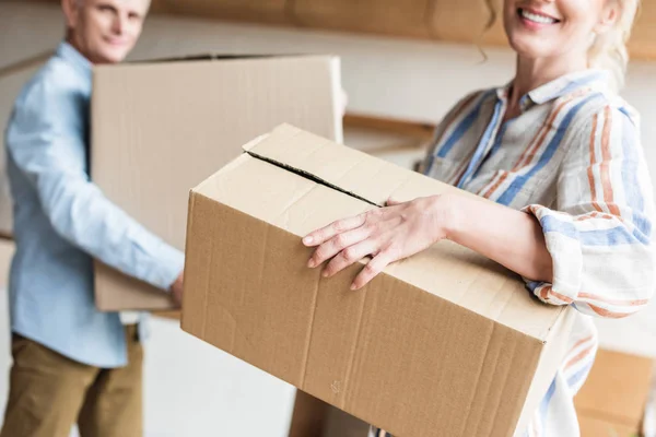 Tiro recortado de pareja de ancianos sosteniendo cajas de cartón y mudanza a casa - foto de stock