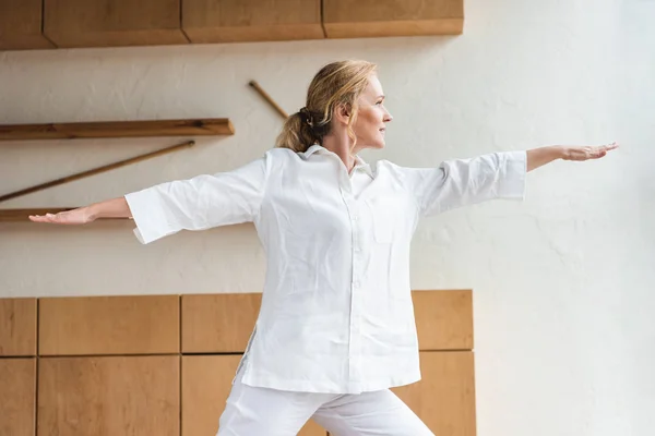 Donna matura sportiva esibendosi posa guerriero durante la pratica dello yoga — Foto stock