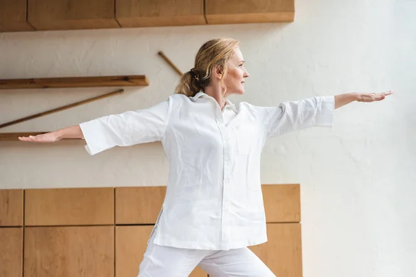Sporty mature woman performing warrior pose while practicing yoga — Stock Photo