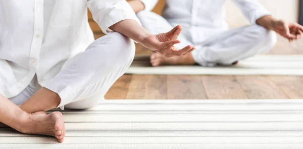 Cropped shot of elderly couple sitting in lotus position and practicing yoga together — Stock Photo
