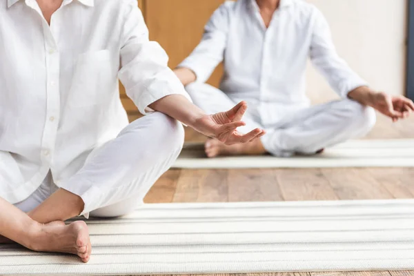 Cropped shot of senior couple sitting in lotus position and practicing yoga together — Stock Photo